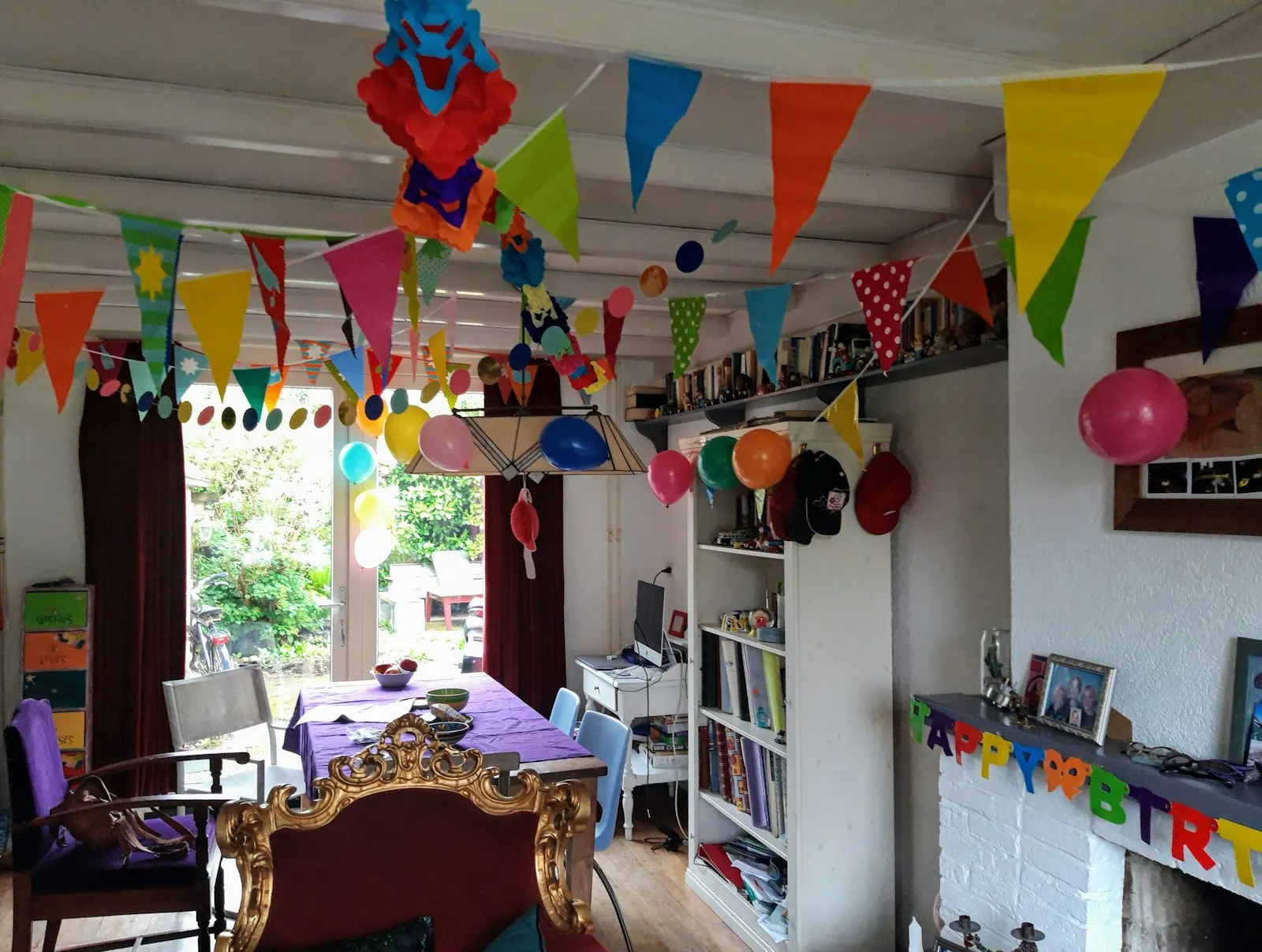 Un salón preparado para una fiesta infantil, con banderines de colores y globos colgados del techo