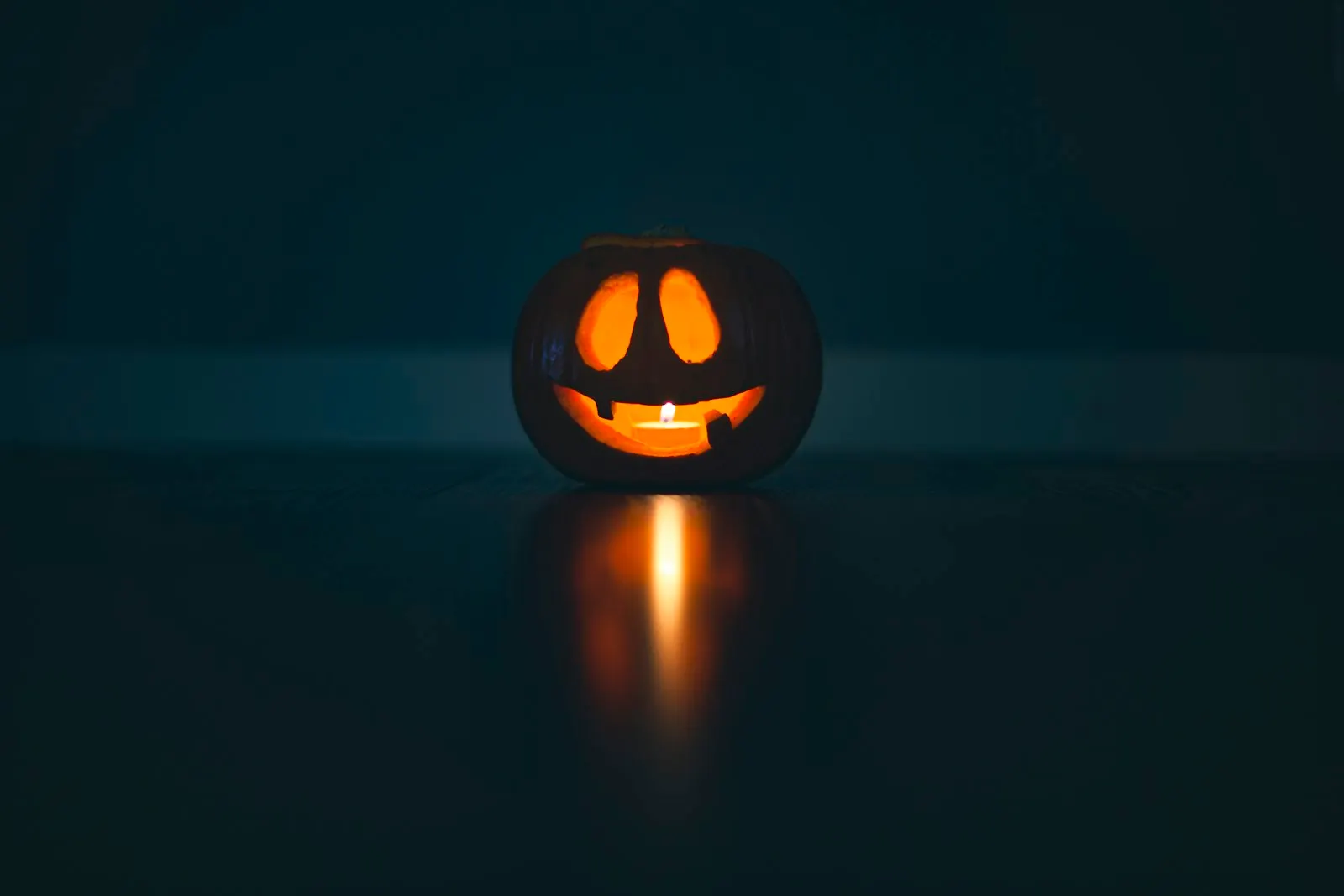 Una calabaza tallada e iluminada por dentro, en una habitación a oscuras