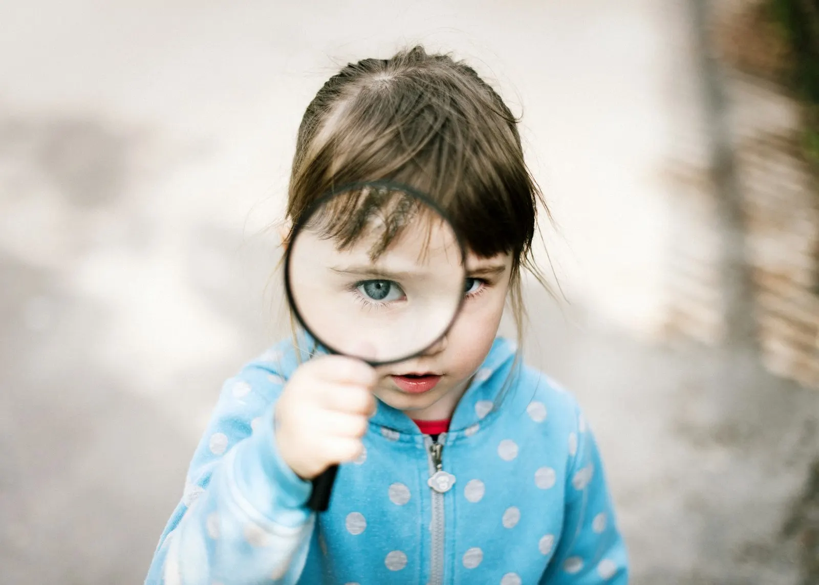 Una niña mira a través de una lupa, con el ojo enorme detrás del cristal
